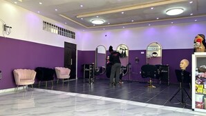 Un salón con paredes moradas, varios espejos y algunas sillas.