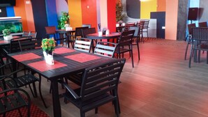Un área de comedor con varias mesas y sillas, un acuario y plantas en macetas.