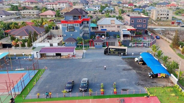 Un edificio de varios pisos con una cancha deportiva y un estacionamiento.