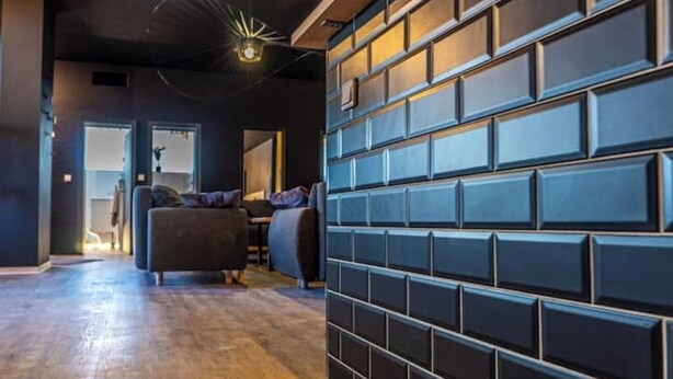 Un interior moderno con pared de ladrillo oscuro, suelo de madera y mobiliario contemporáneo.