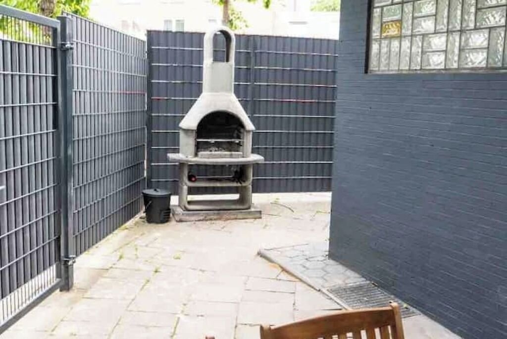 A patio area with a stone floor, a brick oven, and a metal gate.