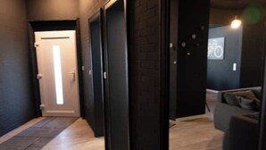 Un pasillo con piso de madera, paredes negras y una puerta al final.