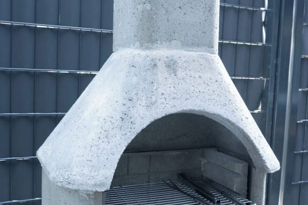 Une structure en béton surmontée d’une grille métallique, qui pourrait servir de barbecue ou d’espace pour faire des grillades.