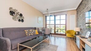 A modern living room with a grey sofa, a glass coffee table, and a yellow armchair. - Jaglana Deluxe 2 by Grand Apartments (Gdansk)