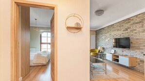 A modern living room with a brick wall, a mounted TV, and a wooden floor. - Jaglana Deluxe 2 by Grand Apartments (Gdansk)