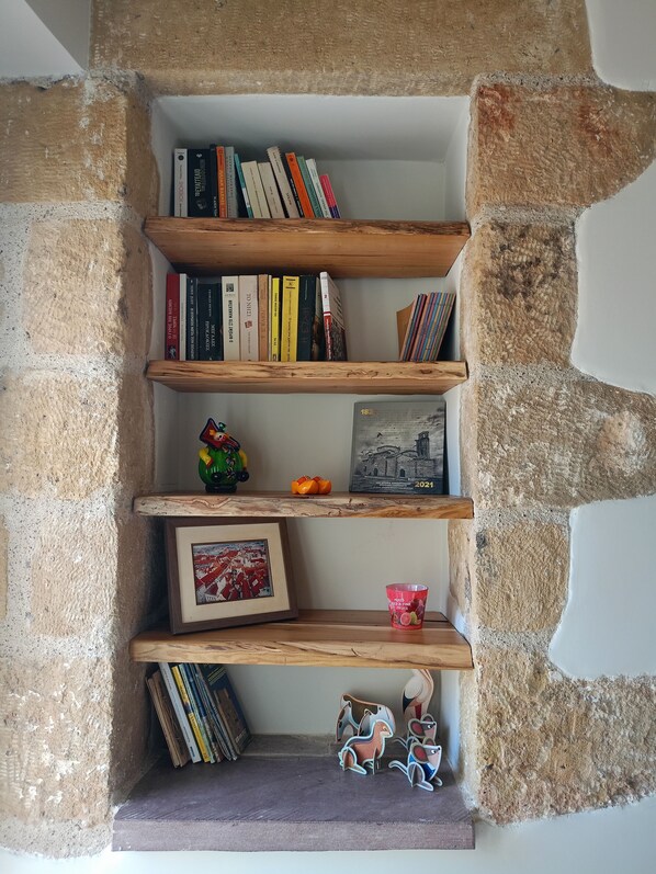 Una estantería con libros, un cuadro enmarco y objetos decorativos.