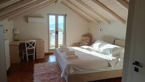 A bedroom with a bed, a desk, a chair, a window, and a door.