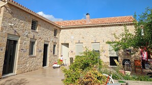 A stone building with a tiled roof, a courtyard, and a child on a scooter.