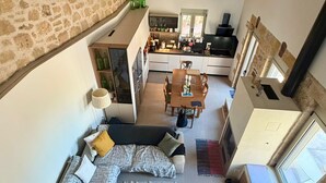 A spacious living area with a stone wall, a sofa, a coffee table, a dining table, and a kitchen area with a stove and cabinets.