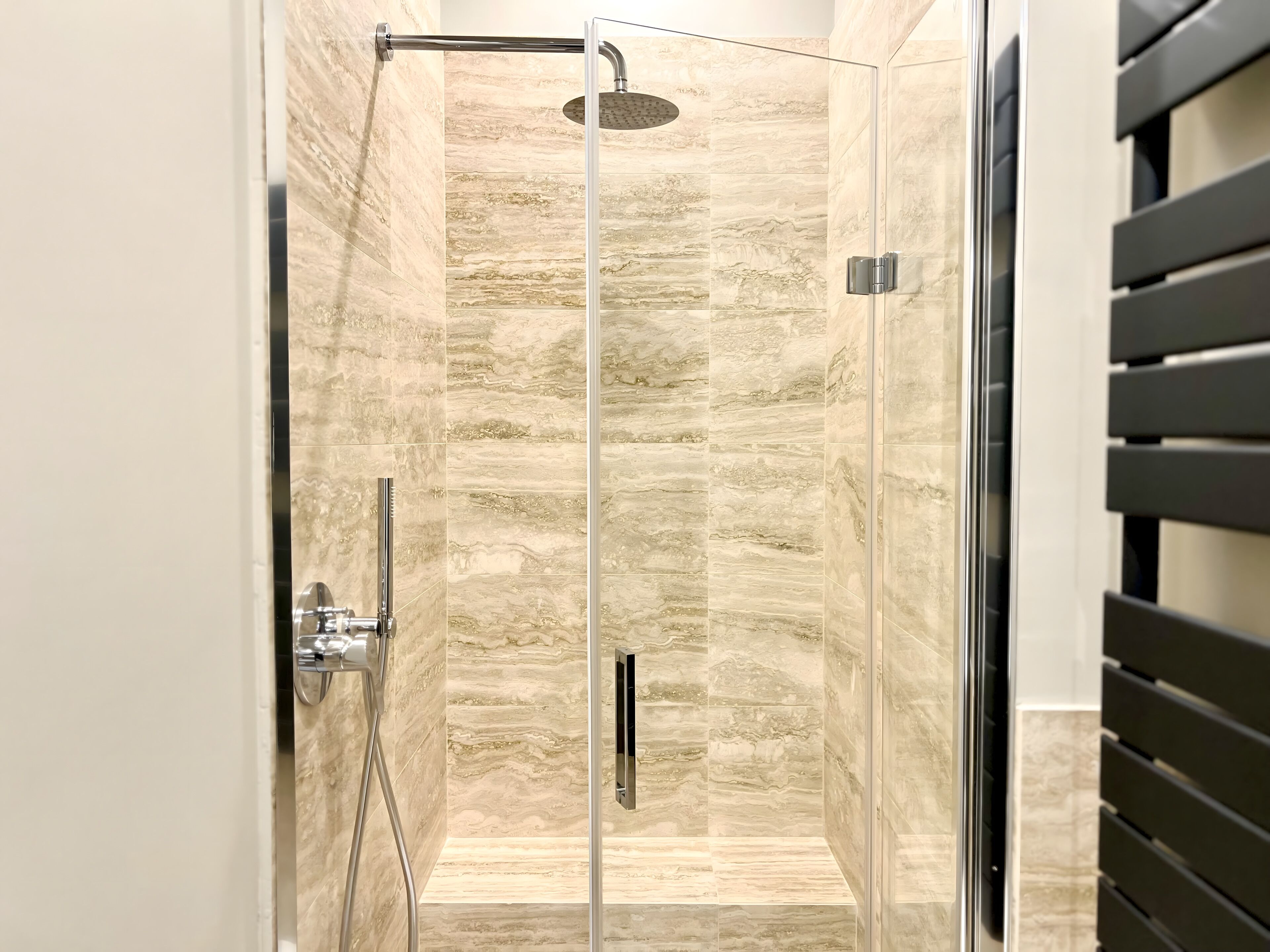 Ducha con paredes de diseño que imitan el mármol, completamente cerrada con cristal.