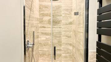 A glass-enclosed shower with a marble-like wall design.