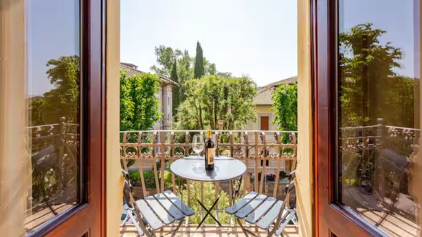 A balcony with a table and chairs, a wine bottle, and a glass. - San Prospero Heritage (Siena)