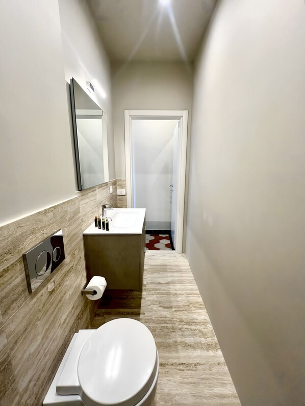 Un baño moderno con inodoro, lavamanos y espejo.