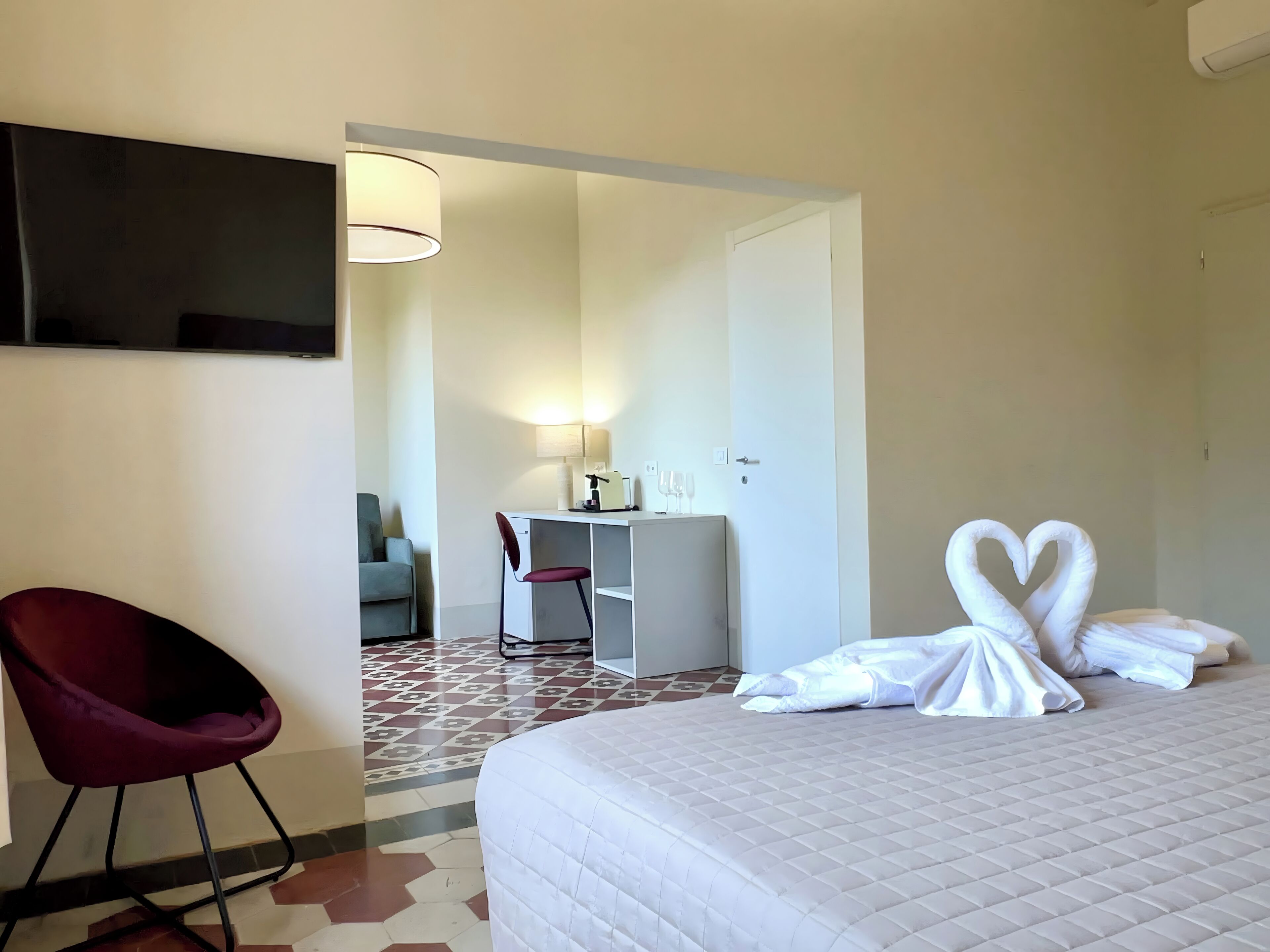 Una habitación de hotel con una cama, un escritorio, una silla y un televisor montado en la pared.
