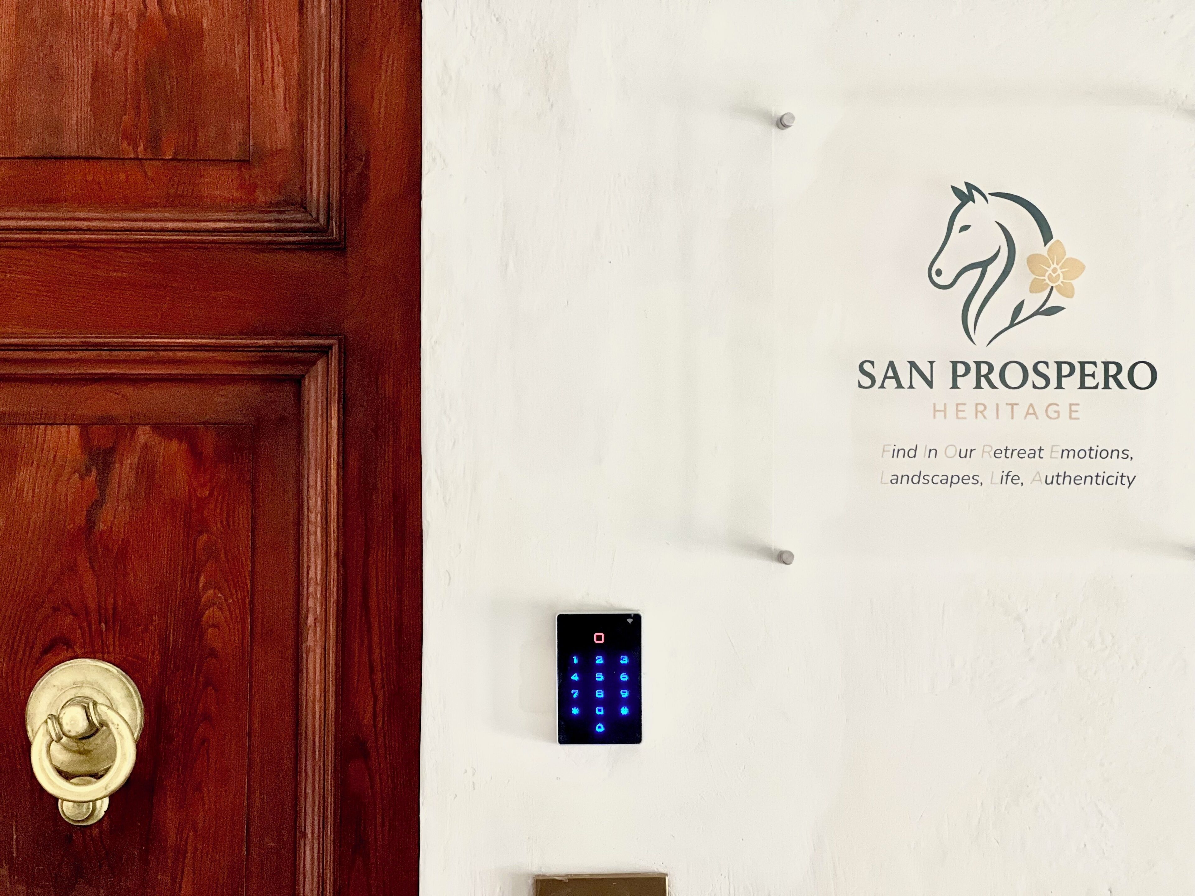 A wooden door with a brass handle and a wall-mounted digital keypad.