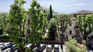 A residential area with parked cars, trees, and buildings with balconies and windows. - San Prospero Heritage (Siena)