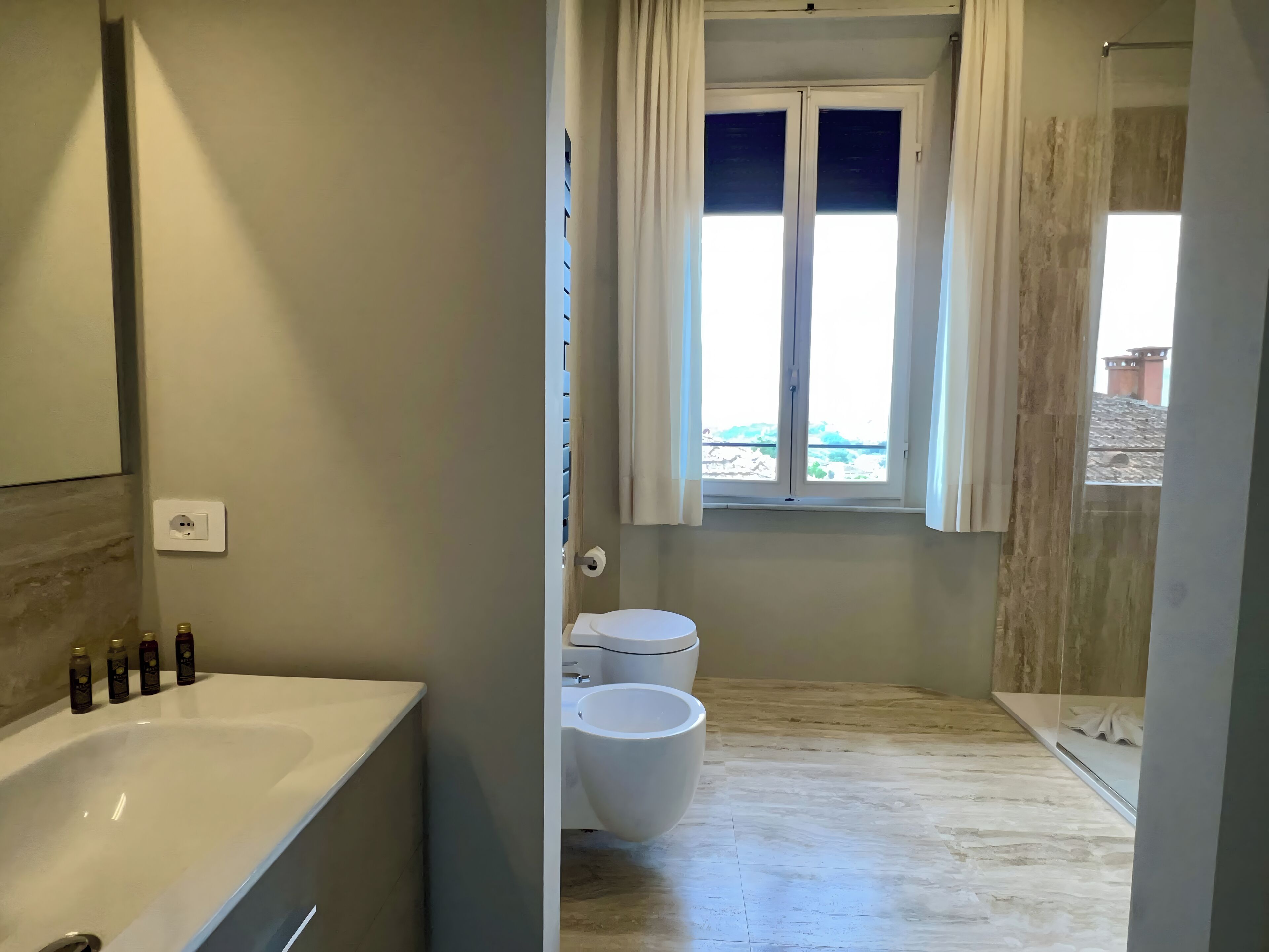 Un baño con bañera, inodoro y ventana con cortinas.