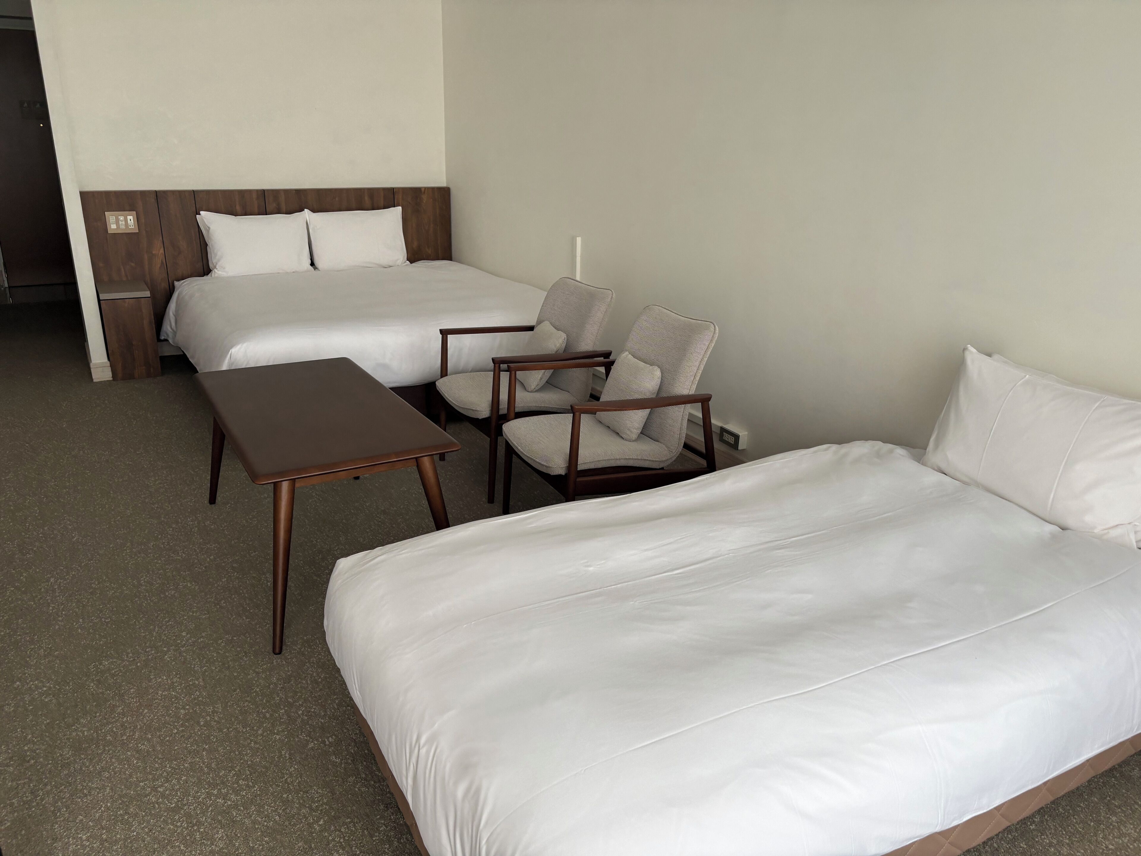Une chambre d ’hôtel avec deux lits, une chaise et une petite table.