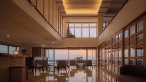 Een ruim interieur met een hoge plafond, grote ramen en een zithoek.
