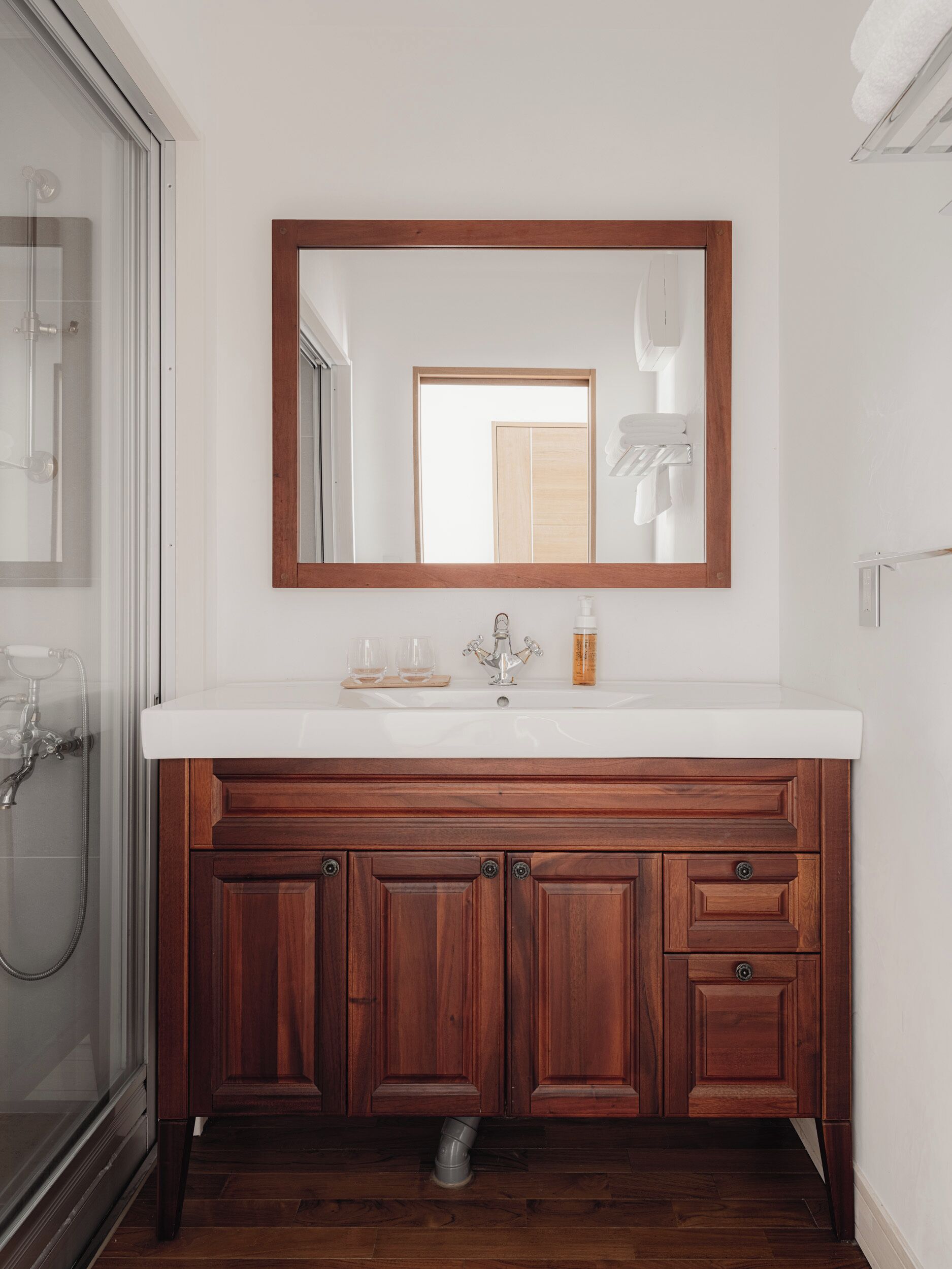 A bathroom with a wooden vanity, a white sink, and a large mirror.