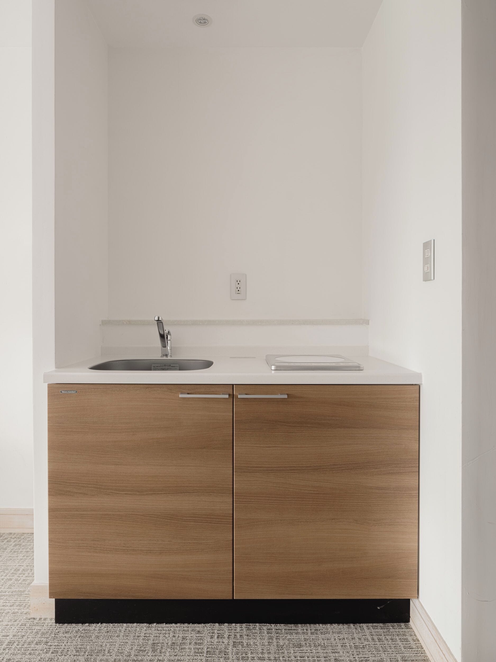 Une cuisine moderne dotée d’un évier à deux bacs, de meubles en bois et d’un plan de travail blanc.