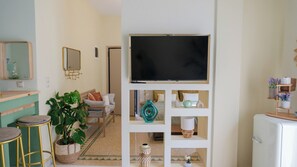 A living room with a TV on a stand, a sofa, a coffee table, and a plant. - Loft w/Rooftop in Athens – Spacious & Peaceful (Athina)
