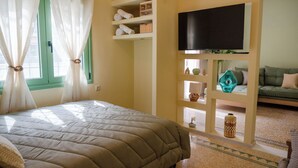 Ein Schlafzimmer mit einem Bett, einem an der Wand befestigten Fernseher und einem Regal mit diversen Gegenständen.