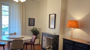 A dining area with a table and chairs, a fireplace, a cabinet, and a window with curtains.