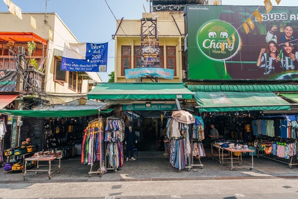 A street market with various stalls selling clothes and accessories.
