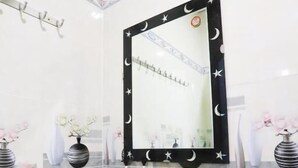 A bathroom with a white sink, a mirror with a black frame decorated with stars and moons, and a shelf with toiletries. - Tram Anh Hotel Dong Nai - by BAY LUXURY (Nhon Trach)