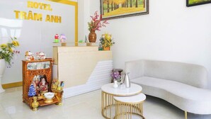 A hotel reception area with a reception desk, a sofa, and a small round table. - Tram Anh Hotel Dong Nai - by BAY LUXURY (Nhon Trach)