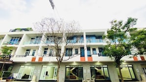 A multi-story hotel with balconies, large windows, and a central staircase. - Tram Anh Hotel Dong Nai - by BAY LUXURY (Nhon Trach)