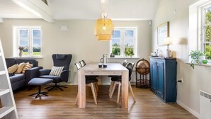 A modern kitchen with a dining area, wooden flooring, and large windows.