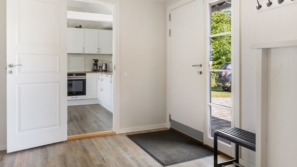 A modern kitchen with white cabinets, a coffee machine, and a built-in oven.