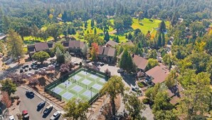 Luftaufnahme eines Wohngebiets mit Häusern, einem Tennisplatz und einem Golfplatz.