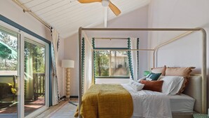 Ein Bett mit Baldachin, eine Lampe und Blick ins Freie durch ein Fenster.