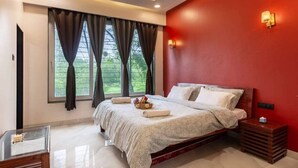 Un dormitorio con cama, mesita de noche, mesa de vidrio y ventana con cortinas.