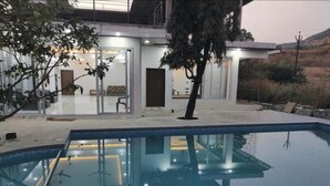 Una casa moderna con piscina, puertas de cristal y zona de patio.