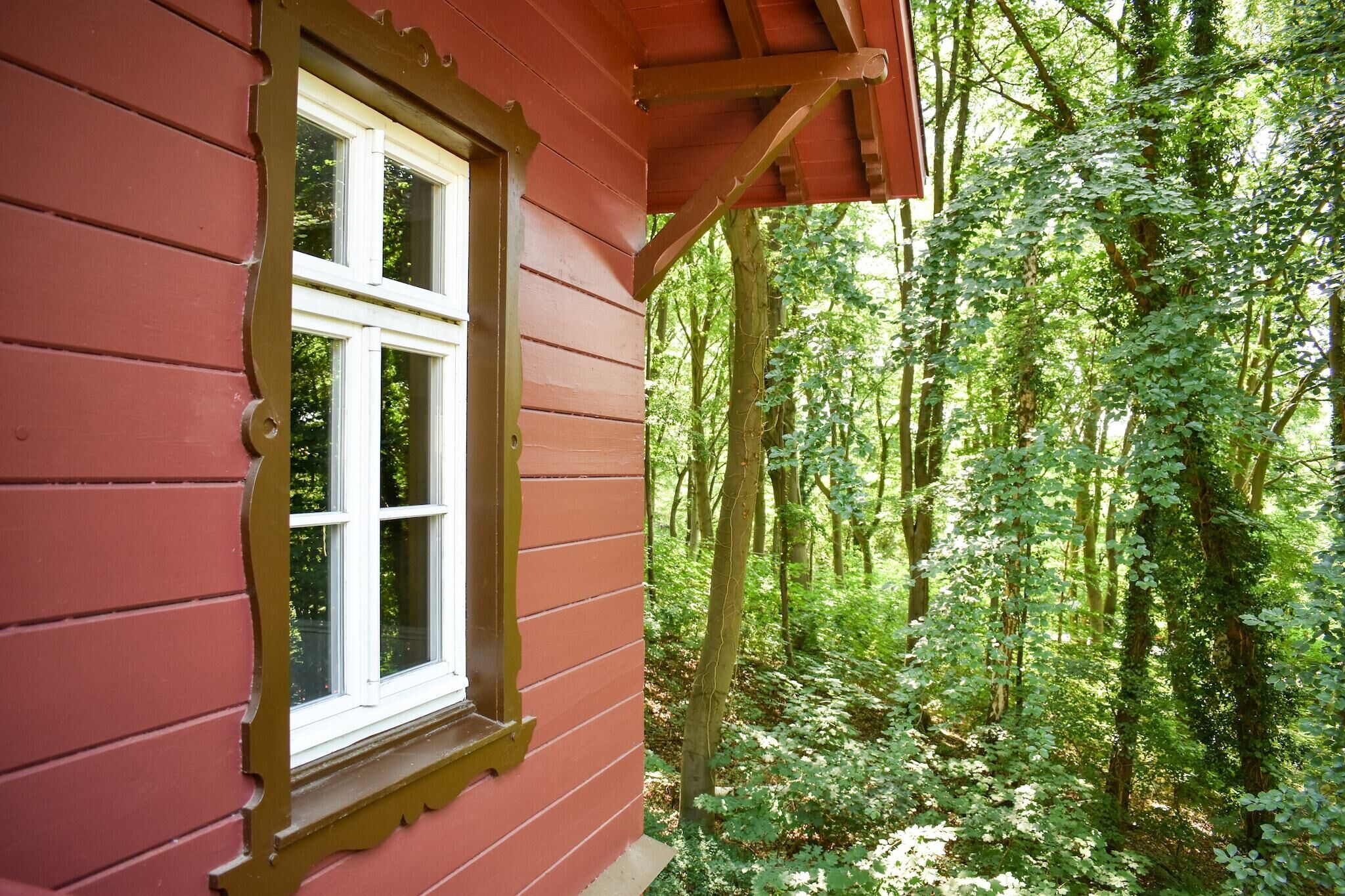 Un edificio di legno rosso con una finestra e vista su una fitta foresta.