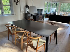 A dining area with a black table and wooden chairs, a TV, and a lamp. - In beautiful Odsherred, northwest Zealand (Nykøbing Sj)