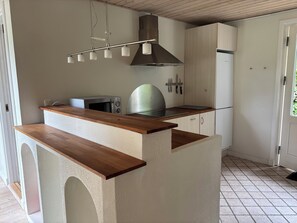 A kitchen with a wooden countertop, a microwave, a stove, and a stainless steel range hood. - In beautiful Odsherred northwest Zealand (Nykøbing Sj)