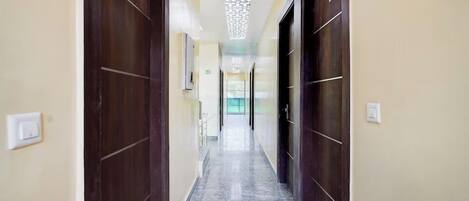 A hallway with marble flooring, dark wooden doors, and a ceiling with a geometric pattern.