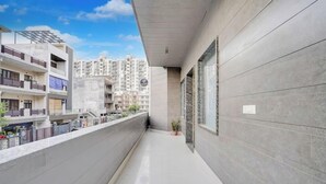 A modern building with a balcony, large windows, and a view of other buildings. - Hotel MoonLit (Noida)
