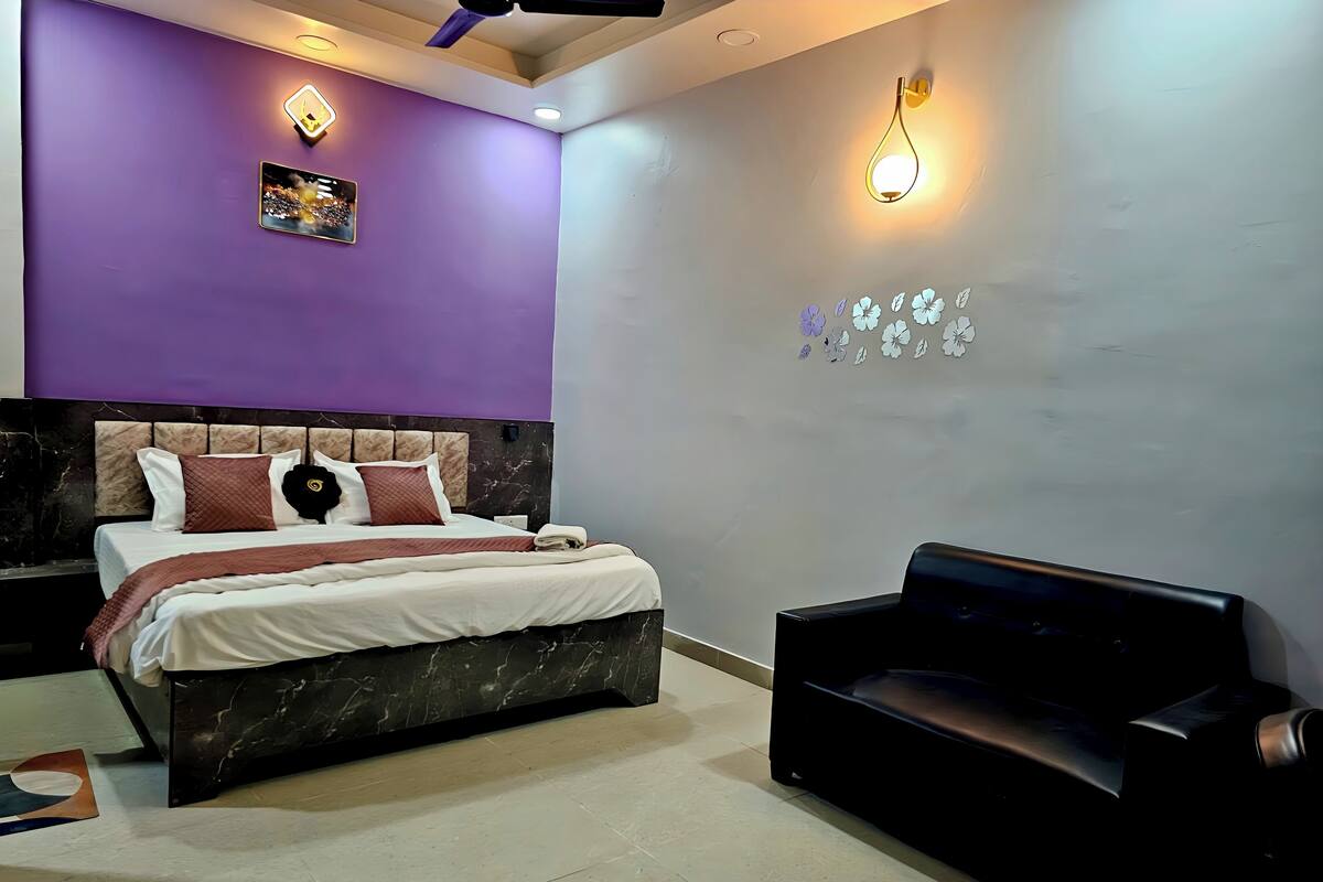 Una habitación de hotel moderna con cama, sofá negro y ventilador de techo.
