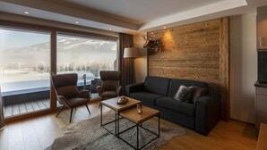 A modern living room with a large window, a wooden accent wall, and a cozy seating area. - Luxurious apartment on the golf course (Westendorf)