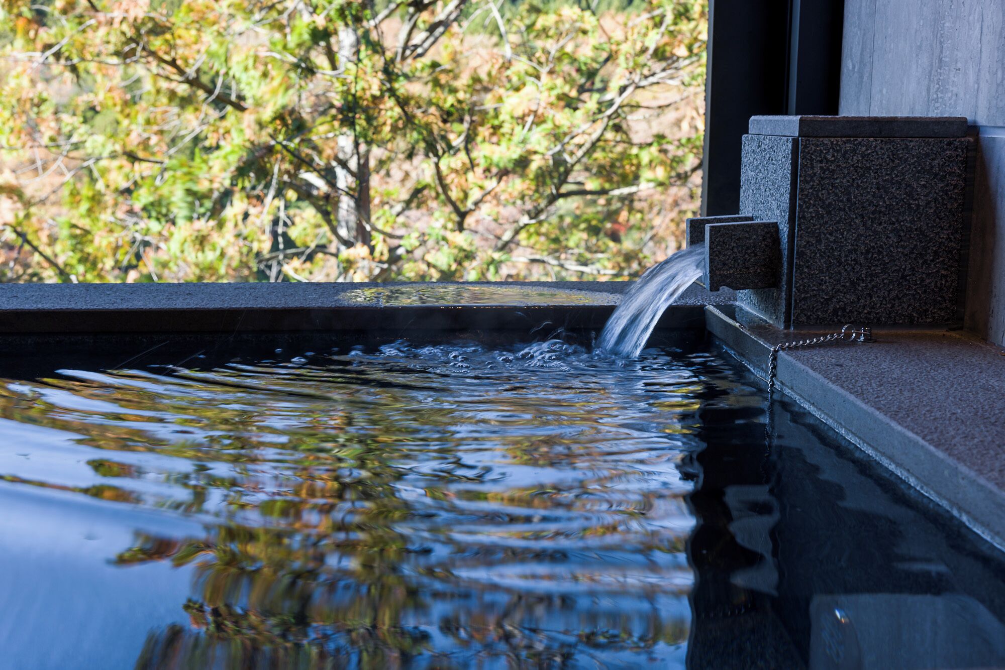 A water feature with a cascading flow into a pool, surrounded by a stone structure.