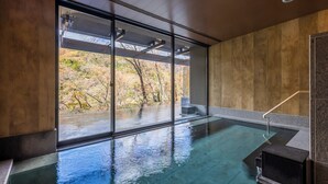 Ein Hallenbad mit Blick auf Herbstbäume und Holzvertäfelung.