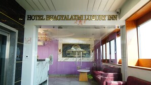 A lobby with a reception desk, a chandelier, purple walls, and seating areas. - HOTEL BHAGYALAXMI LUXURY INN (Gandhinagar)
