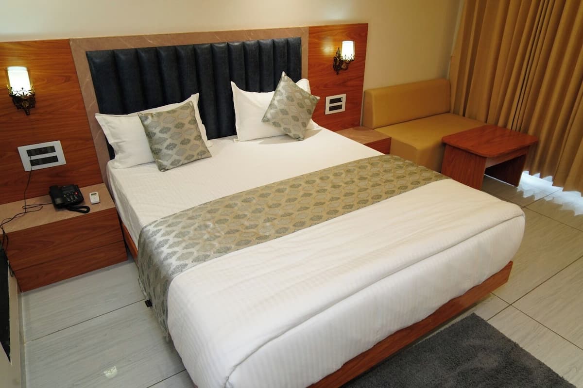A hotel room with a large bed, bedside tables, a telephone, and a lamp.