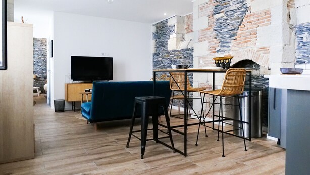 Una sala moderna con un sofá azul, dos sillones de mimbre, una mesita y un televisor.